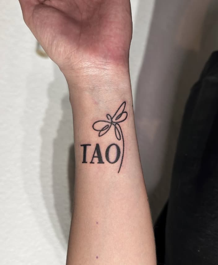 Tatuaje libélula con palabra Tao en muñeca – Cheno Tattoo Pachuca